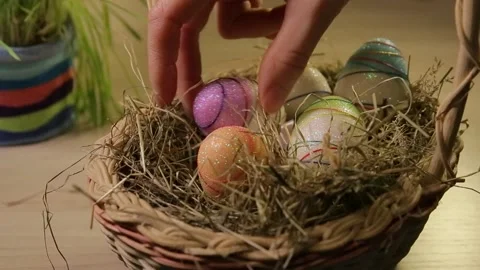 A woman puts Easter eggs in a basket with hay. Only hands. Easter decorations Stock Footage 106059457