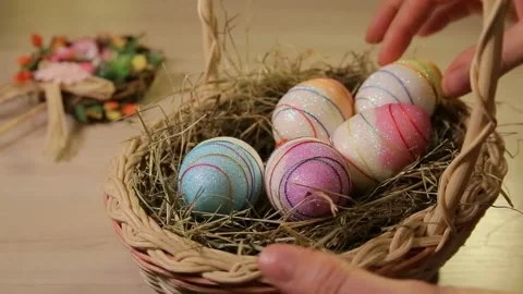A woman puts Easter eggs in a basket with hay. Only hands. Easter decorations Stock Footage 106149805