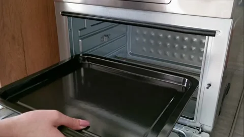 A woman puts an empty baking tray in the oven Stock Footage 152557268