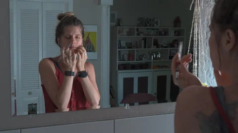 Woman puts on eyeliner while looking into a mirror Stock Footage 280588207