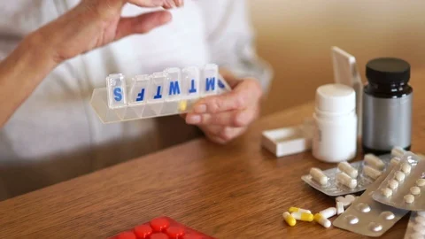 A woman puts her pills in a plastic container. Pensioner takes a daily dose of Stock Footage 104955152
