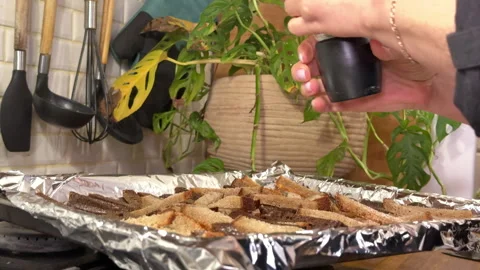 A woman puts pieces of rye bread on a baking tray to make breadcrumbs Stockbeeldmateriaal 301248495