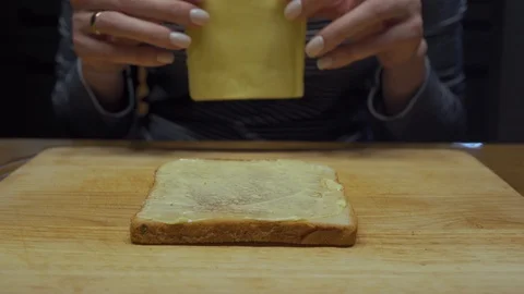 Woman puts a slice of cheese on bread and butter Stock Footage 102984235