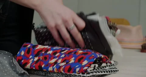Woman puts stack of cloth with bright patterns on table Stock Footage 207461570
