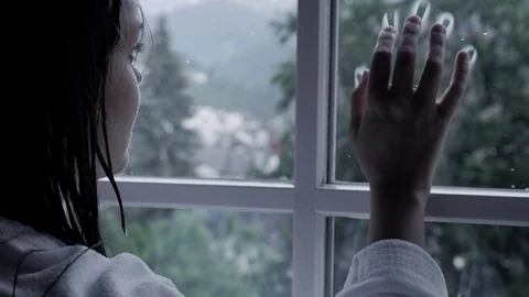 Woman putting hand on window in front of rain sad slow motion Stock Footage