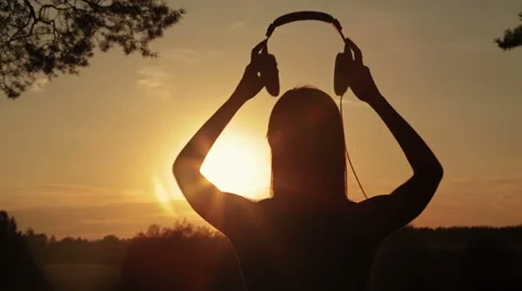 Woman putting on the headphones, listening to music and dancing in the forest Stock Footage