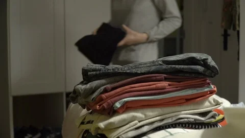 Woman is putting ironed clothes on stack. Dry ironed laundry on stack. Stock Footage 107959490