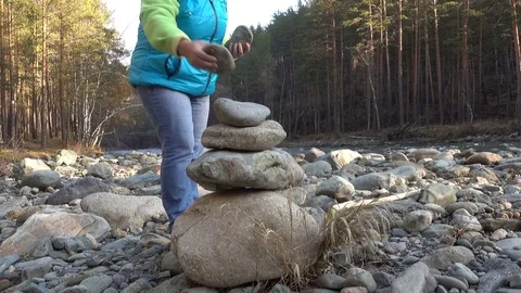 Woman putting pebble stack Видео 81180278