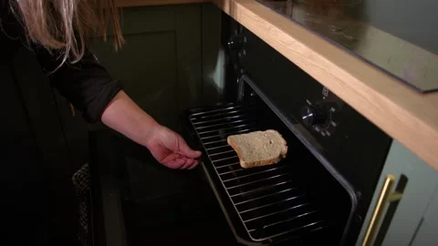 Woman putting slice of bread in oven grill to make toast Video stock 346042614