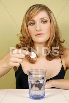 A woman putting a tablet in a glass of water. Stock Photos