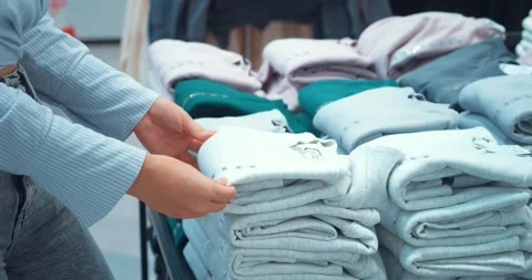 Woman putting things back in stack in clothing store. Individuality and self Stock Footage 257700557