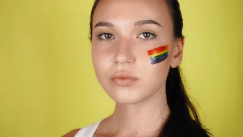A woman with a rainbow pattern on her face looks proudly into the camera Vídeo Stock 137014961