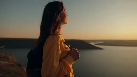 Woman raises her hands up while standing on top of a rock mountain above the sea Stock Footage 239909161