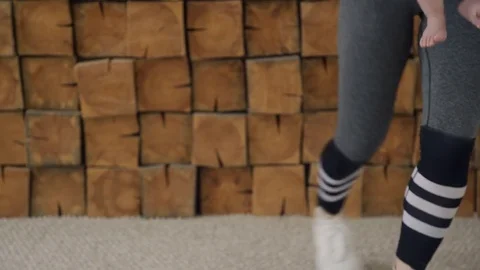 Woman raises her leg to side and squats down with baby in arms in gym. Stock Footage