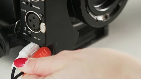 Woman Re-plugging a White Cable to a Video Camera Stock Footage 69789651