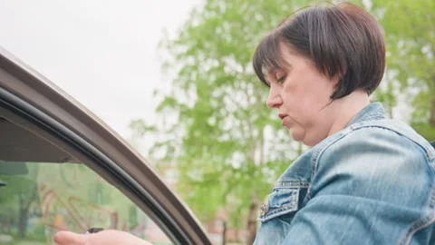 Woman Reaching For Jacket At Car Door, Inspecting Fabric And Zipper, Preparing Stock Footage 324202953