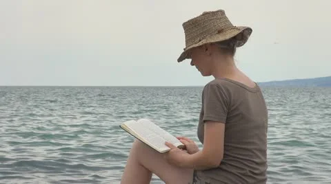 Woman read on the beach rock coastline stone sea ocean exotic lifestyle girl Stock Footage
