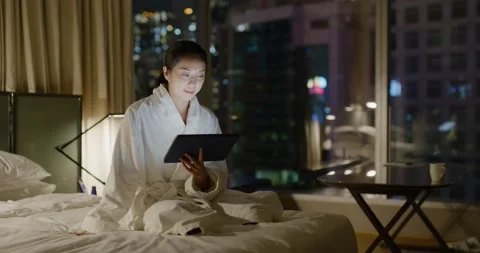 Woman read on tablet computer and sit on bed at night Video stock 169414277