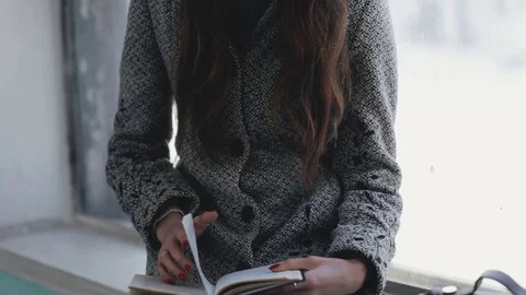 Woman reading book in old public building sitting on windowsill Stock Footage