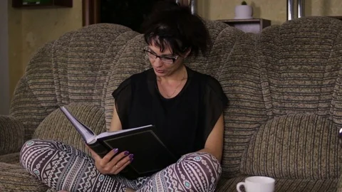 Woman reading book on sofa Stock Footage