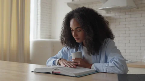 Woman Reading Book At Table With Focused And Calm Expression Stock Footage 344696957