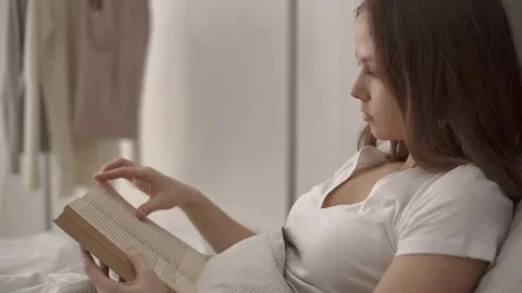 Woman reading a book while lying in bed Stock Footage 132050991