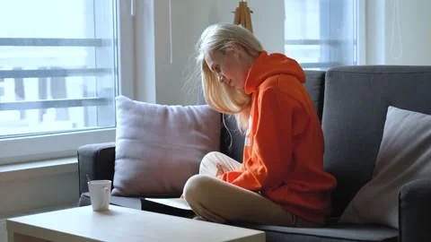Woman reading a book while sitting on the couch at home Stock Footage 166519837