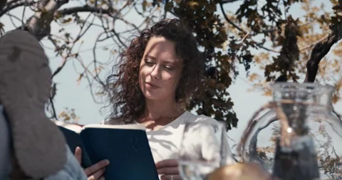 A woman is reading a book while sitting on a bench Stock Footage 283763269