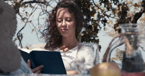 A woman is reading a book while sitting at a table Stock-Footage 283763540