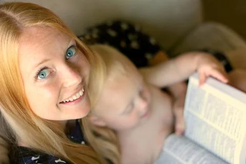 Woman reading book while while holding baby Stock Photos