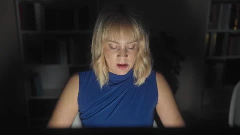 Woman reading on computer screen in studio, head down and lit by monitor gl.. Stock-Footage 337386294