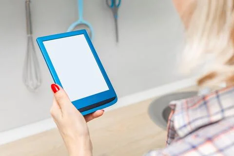 Woman reading e-book in kitchen at home. Stock Photos