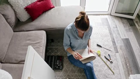 Woman reading instruction while assembling DIY furniture at home. Vidéo 132587576