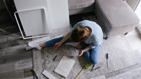 Woman reading instruction while assembling DIY furniture at home. Stock Footage 132588593