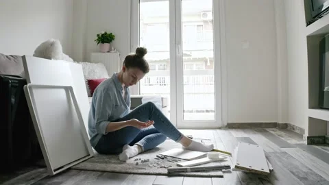 Woman reading instruction while assembling DIY furniture at home. Video stock 132589520