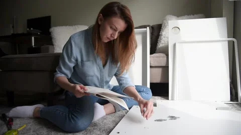 Woman reading instruction while assembling DIY furniture at home. Stock Footage 132591798