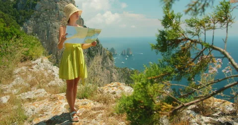 Woman reading a map on a cliffside path overlooking Capri island and distant Stock Footage 344777647