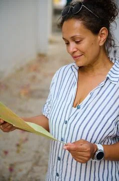 Woman reading a map outdoors while traveling, relaxed and thoughtful on vac.. Фото