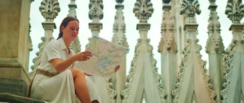 Woman reading map on steps of Duomo rooftop surrounded by spires in Milan, Italy Stock Footage 344705088