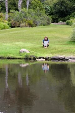 Woman reading newspaper sitting in grass Stock Photos