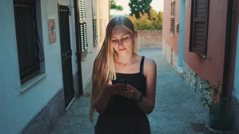 Woman reading something on smartphone while walking the street Stock Footage 142920069