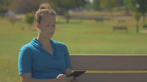 Woman Reading Tablet E-Book on Park Bench Vídeo Stock 55240858