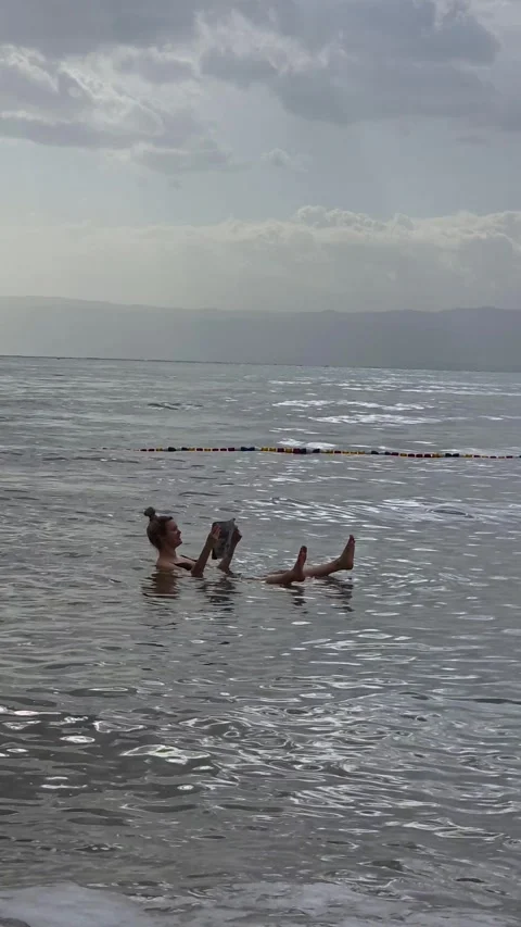Woman reading while floating in the Dead Sea, Jordan. Vertical Stock Footage 331189470