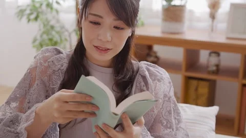 A Woman Reading While Sitting on a Sofa Vidéo 332750772