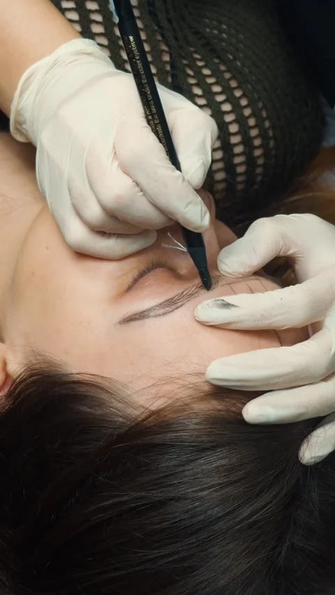Woman receiving microblading procedure, having eyebrows mapped and designed with Stock Footage 331573989
