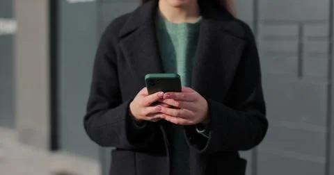 Woman receiving parcel from post terminal machine using smartphone outdoors. Foto stock