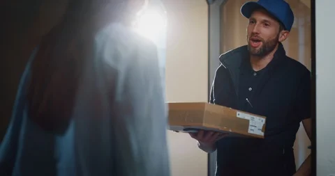 Woman receiving using smartphone for digital signing a parcel delivered at home. 動画素材 114677723