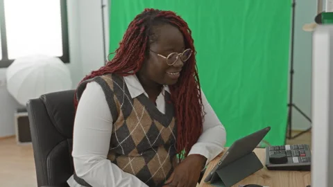 Woman with red braids using tablet at studio desk with green screen and sof.. Stock Footage 337419413