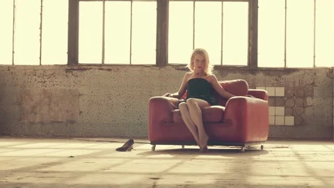Woman in a red chair in the rays of light 库存影片 113016953