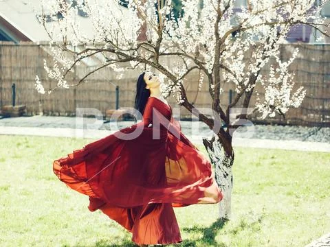 Woman in red dress near blossom Stock Photos